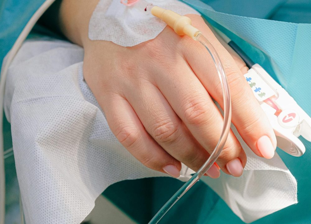 Close-up of a patient's hand receiving intravenous therapy in a hospital setting.