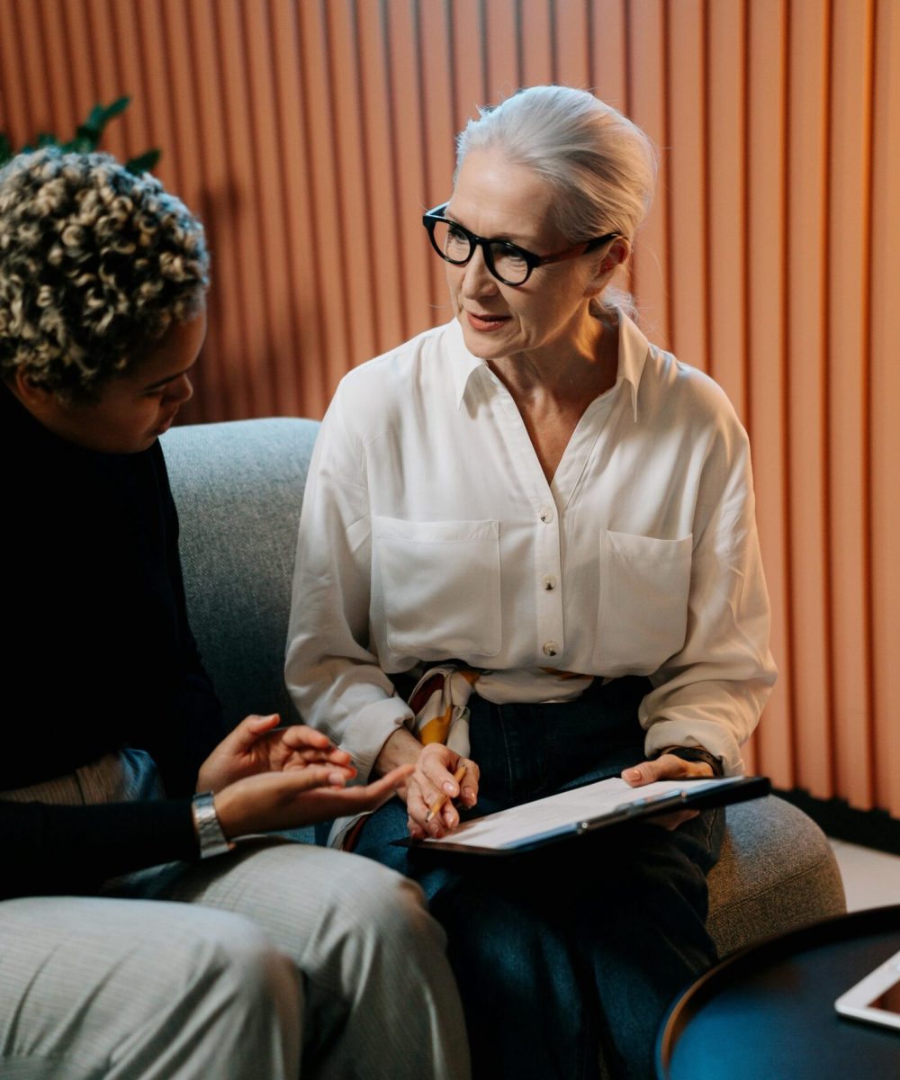 Two professional women engaged in a business discussion indoors with documents.