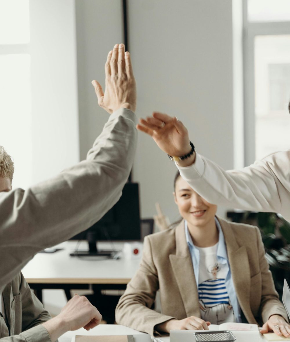 Colleagues in an office exchanging a high five, symbolizing teamwork and success.